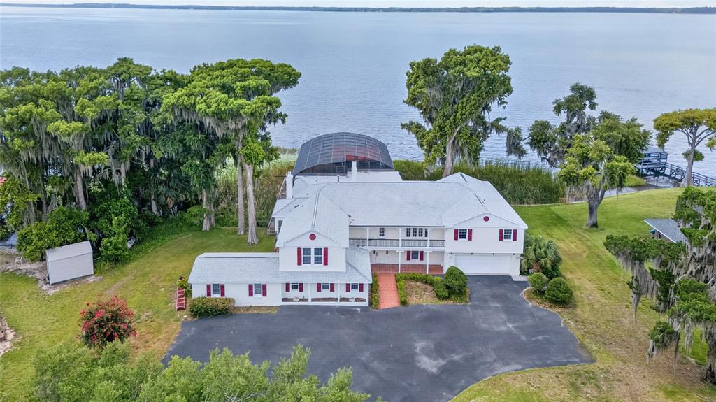 An aerial view of a white two-story house with a screened pool enclosure by a lake — 1029 MELLATHON CIRCLE, LEESBURG, FL