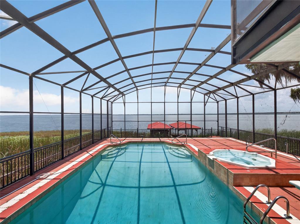 A screened-in swimming pool and hot tub overlook a lake with boat docks — 1029 MELLATHON CIRCLE, LEESBURG, FL