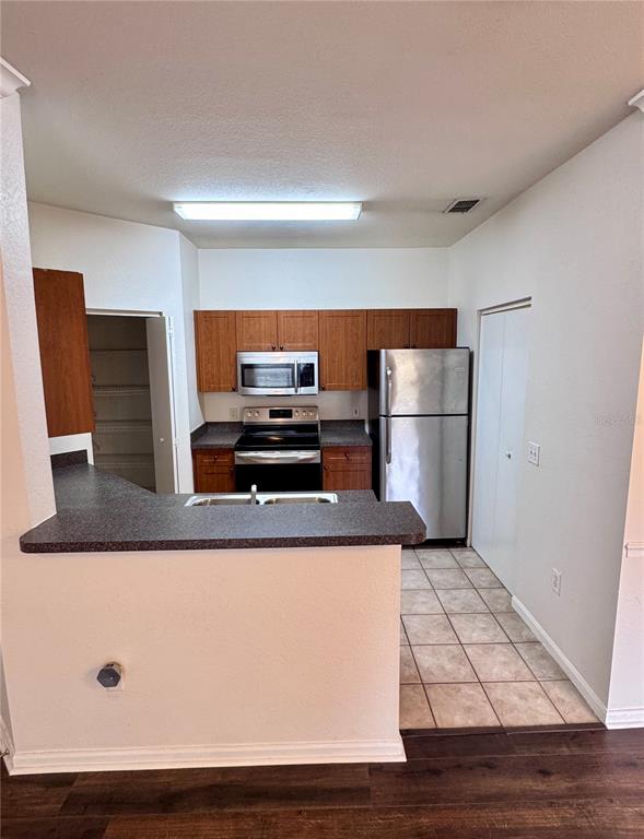 A kitchen features wood cabinets, black appliances, gray countertops, and light-colored wood-look flooring — 2249 PORTOFINO PLACE UNIT 22-2217, PALM HARBOR, FL