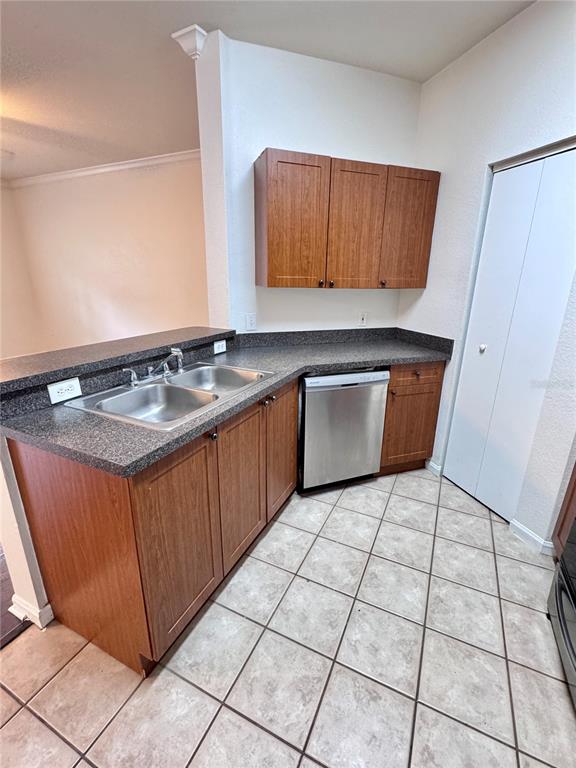 A kitchen with wood cabinets, black appliances, and a doorway leading to a laundry area — 2249 PORTOFINO PLACE UNIT 22-2217, PALM HARBOR, FL