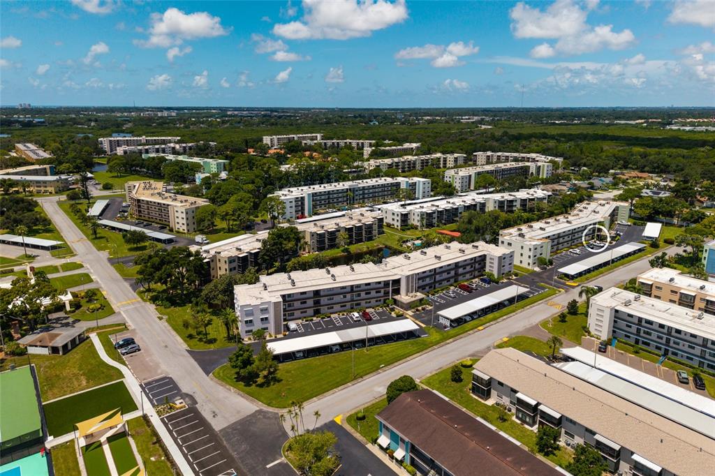 An aerial view shows multiple multi-story apartment buildings surrounded by parking lots and green space — 5980 TERRACE PARK DRIVE N UNIT 108, ST PETERSBURG, FL