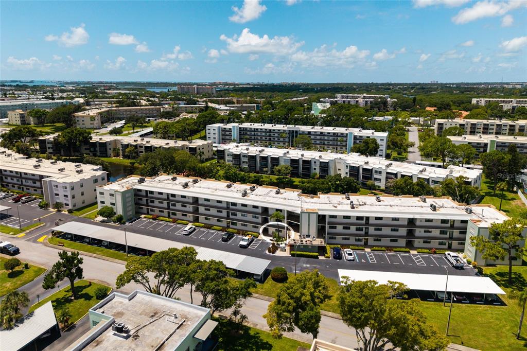An aerial view shows a multi-story apartment complex with parking lots and surrounding green space — 5980 TERRACE PARK DRIVE N UNIT 108, ST PETERSBURG, FL