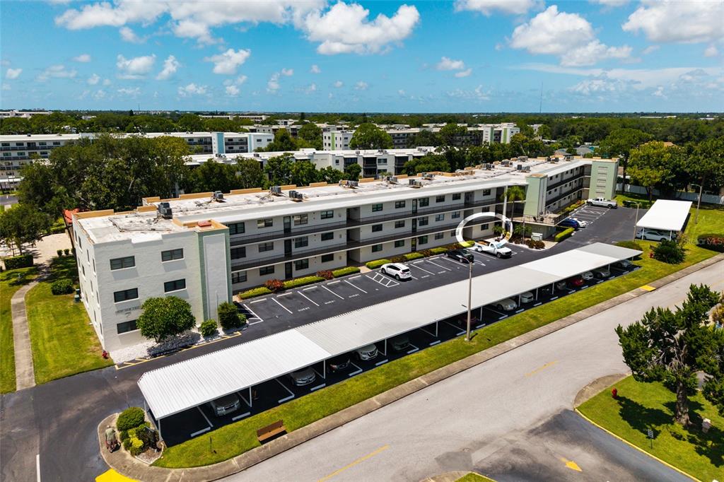 An aerial view of a multi-story apartment building with covered parking spaces and landscaped grounds — 5980 TERRACE PARK DRIVE N UNIT 108, ST PETERSBURG, FL