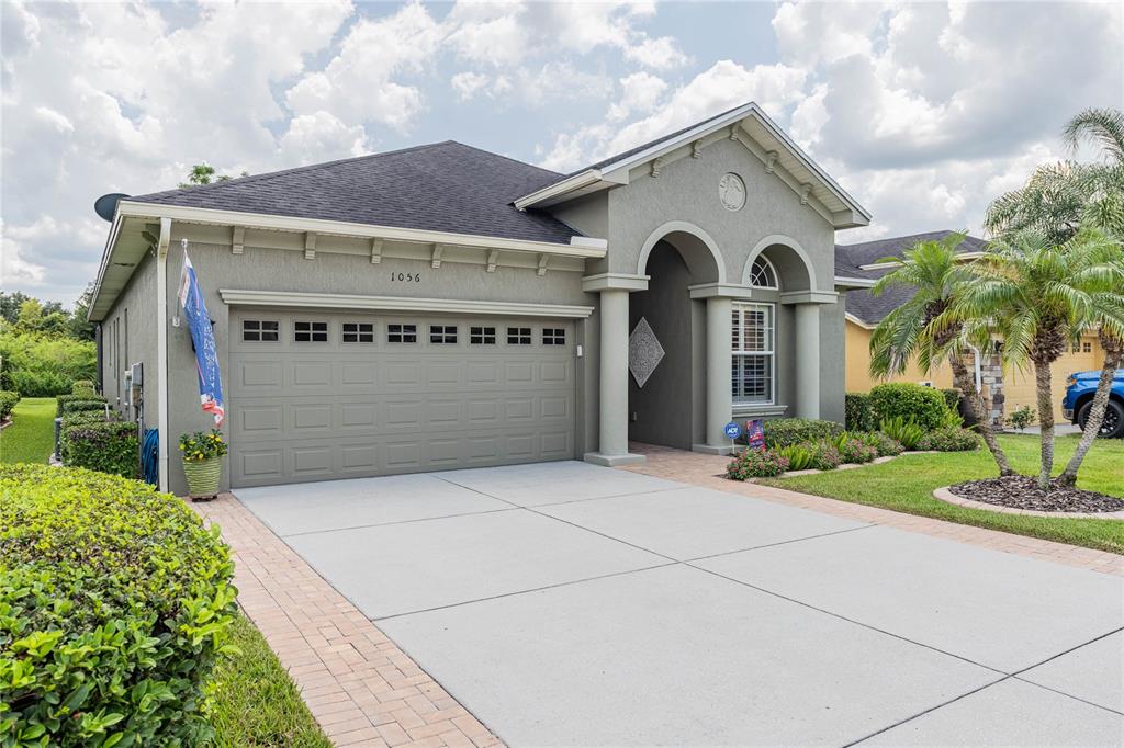 A single-story house with a gray stucco exterior, a two-car garage, and a paved driveway — 1056 STONEY CREEK DRIVE, LAKELAND, FL