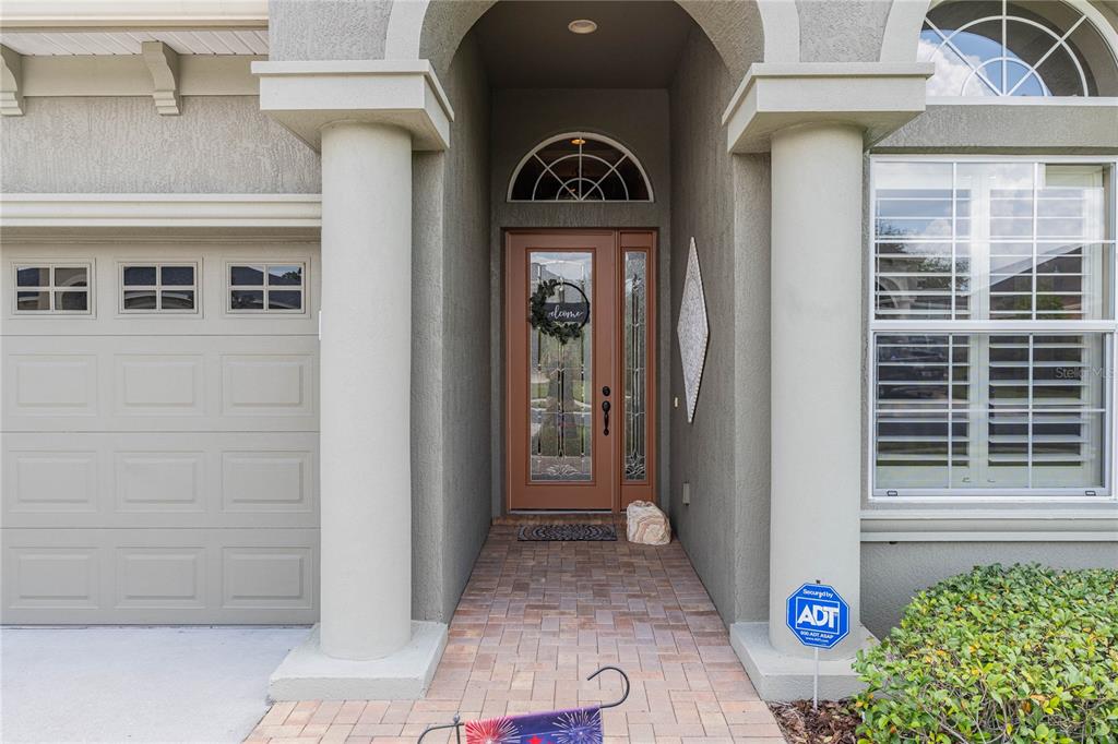 The exterior of a house features a brick walkway, a front door, and two columns — 1056 STONEY CREEK DRIVE, LAKELAND, FL