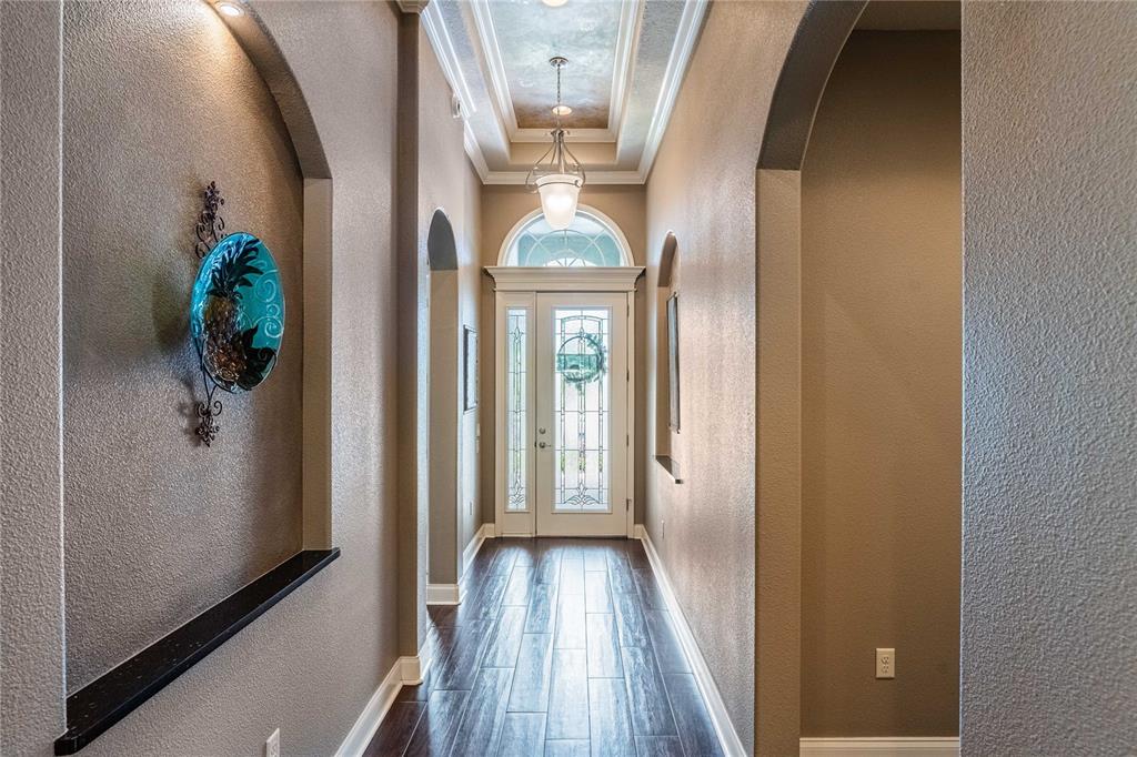 A hallway with dark wood floors, arched wall niches, and a glass-paneled front door — 1056 STONEY CREEK DRIVE, LAKELAND, FL