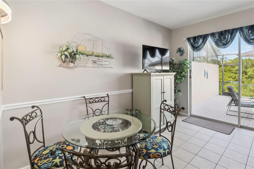 A dining area features a glass-topped table, metal chairs, and a sliding door to a patio — 2382 SILVER PALM DRIVE E, KISSIMMEE, FL