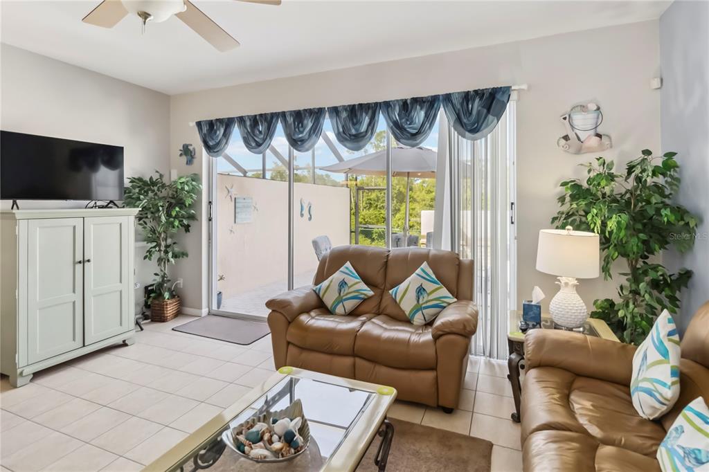 A living room features tile floors, two leather sofas, a television, and sliding glass doors — 2382 SILVER PALM DRIVE E, KISSIMMEE, FL