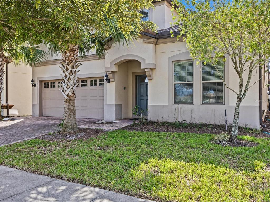 A two-story stucco house features a two-car garage, a covered entryway, and a front lawn — 8832 MACAPA DRIVE, KISSIMMEE, FL