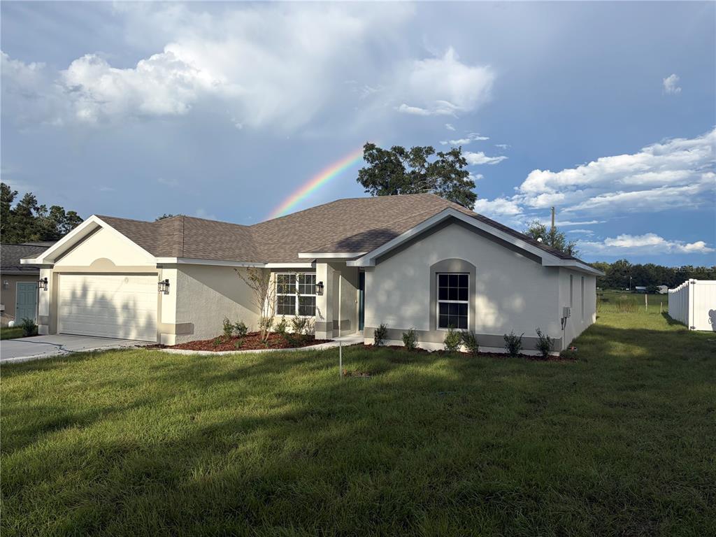 A single-story house under construction features a garage, stucco exterior, and an open drainage system — 15691 SE 97TH AVENUE, SUMMERFIELD, FL
