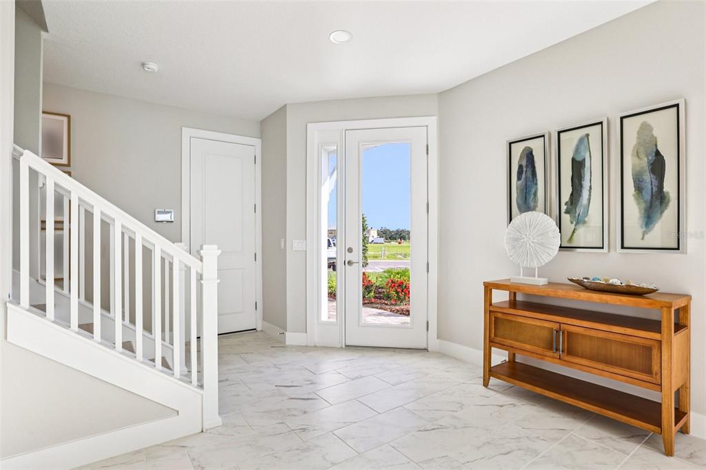 A bright entryway features white tile floors, a wooden console table, and a white staircase — 31493 SPANISH MISSION ROAD, SAN ANTONIO, FL
