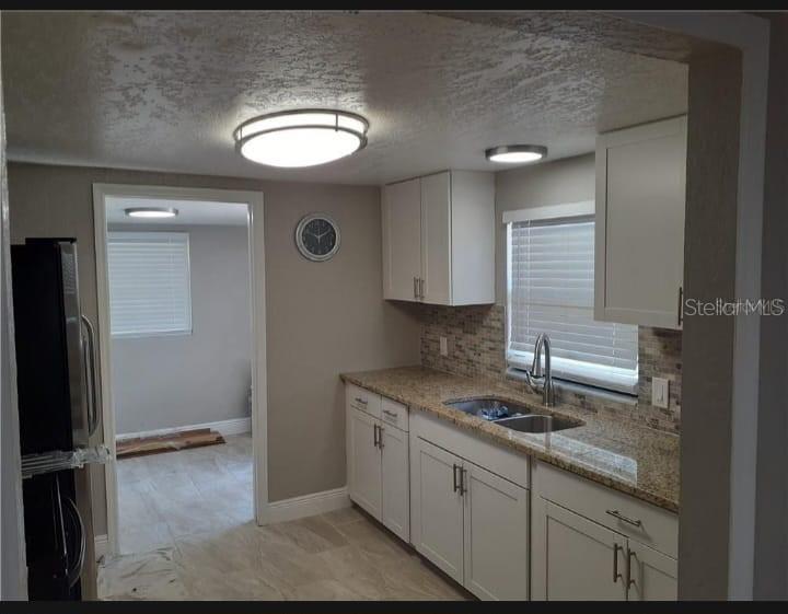 A kitchen with white cabinets, granite countertops, a tiled backsplash, and a view into another room — 3602 N 55TH STREET, TAMPA, FL