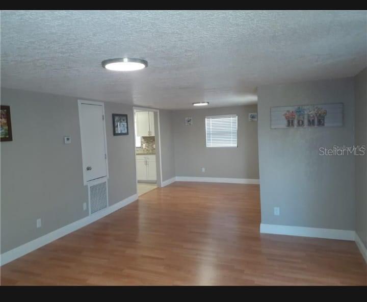 An open-concept living area features light gray walls, wood-look flooring, and a view into a kitchen — 3602 N 55TH STREET, TAMPA, FL