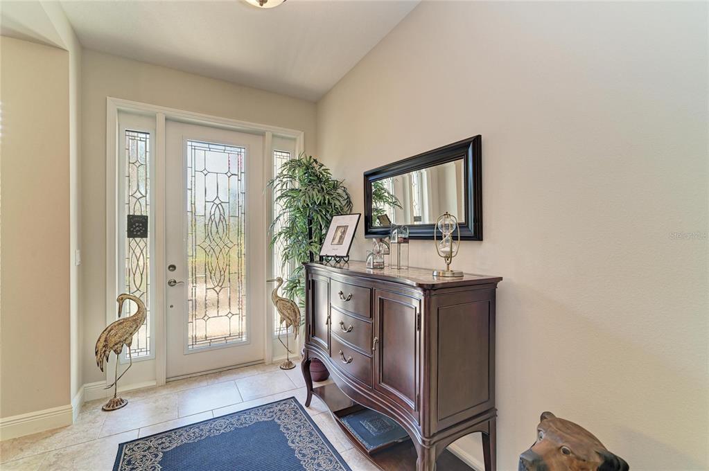 An entryway features a glass-paneled front door, a dark wood console table, and a mirror — 517 CHANTILLY TRAIL, BRADENTON, FL