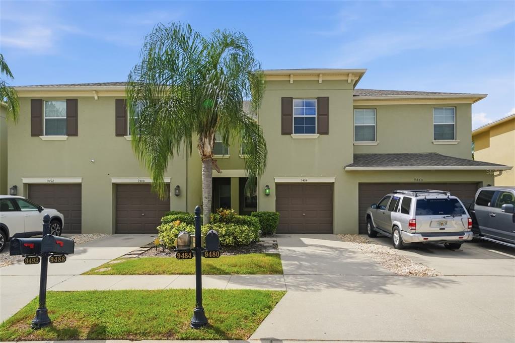 A two-story multi-unit residential building with four garage doors and a palm tree out front — 9484 TRUMPET VINE LOOP, TRINITY, FL