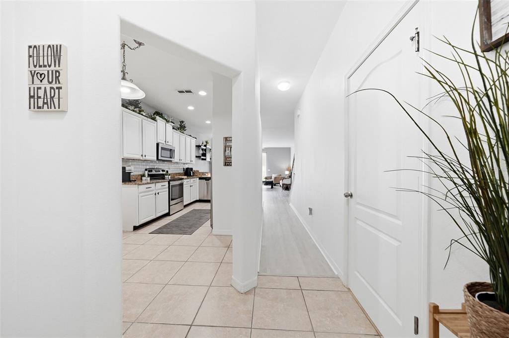 A tiled entryway leads to a white kitchen and a hallway with light-colored flooring — 9484 TRUMPET VINE LOOP, TRINITY, FL
