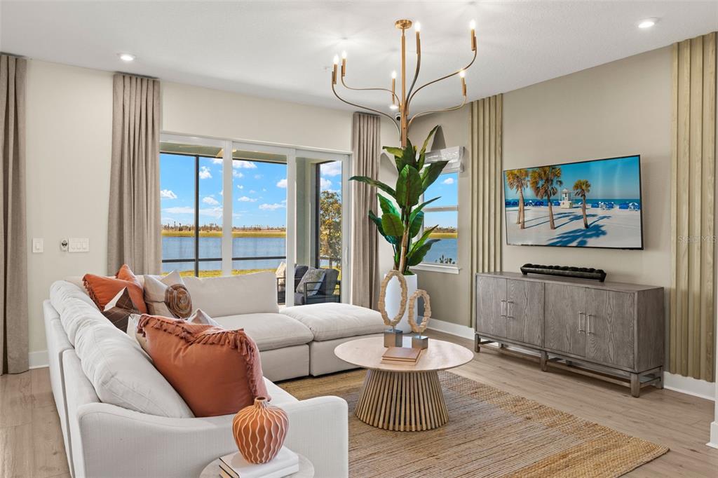 A living room features a sectional sofa, a round coffee table, and a view of water — 12766 JADE EMPRESS LOOP UNIT 101, VENICE, FL