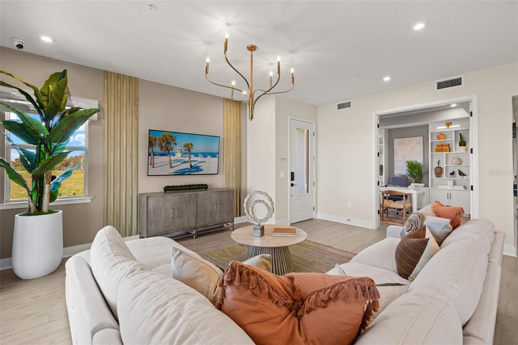 A living room features a white sectional sofa, a television, and an adjacent home office — 12766 JADE EMPRESS LOOP UNIT 101, VENICE, FL