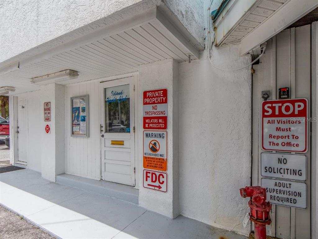Exterior view of a building entrance with multiple warning signs and a red fire hydrant — 200 WINDWARD PASSAGE UNIT 66, CLEARWATER BEACH, FL