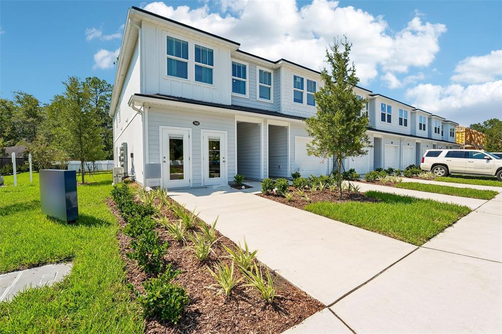 A two-story townhouse exterior with light blue siding, white trim, and a concrete driveway — 7657 COMMANDER LANE, JACKSONVILLE, FL