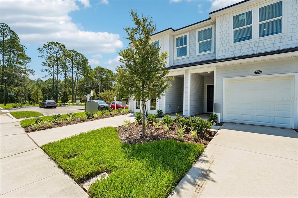 A two-story townhouse exterior with a white garage, light blue siding, and a front lawn — 7657 COMMANDER LANE, JACKSONVILLE, FL