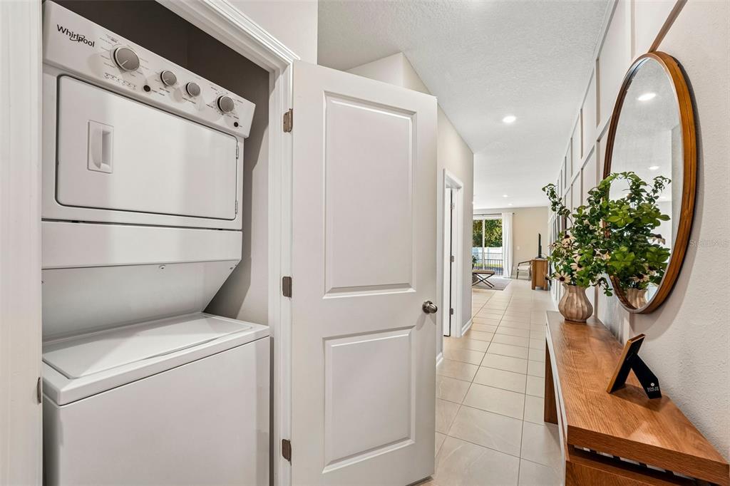 A stacked Whirlpool washer and dryer sit in a closet next to a hallway entryway — 7657 COMMANDER LANE, JACKSONVILLE, FL