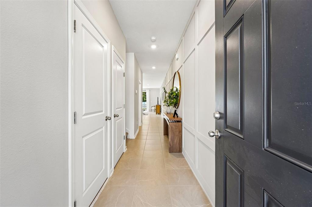 A long hallway with tiled floors, white paneled walls, and a dark front door — 7657 COMMANDER LANE, JACKSONVILLE, FL