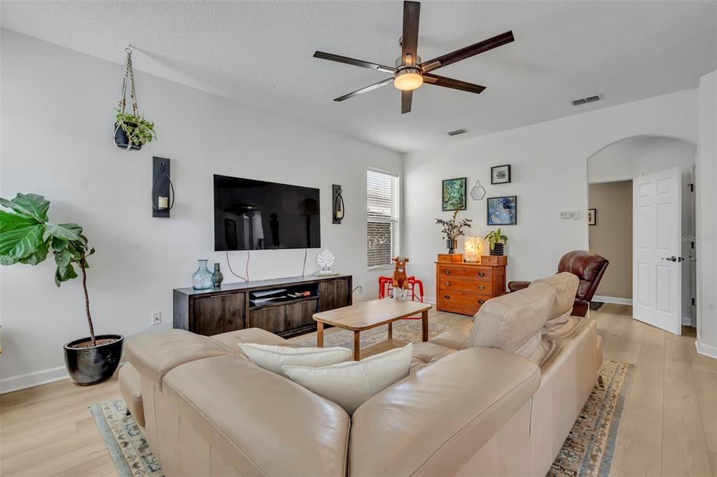 A living room features a tan sectional sofa, a dark wood media console, and a ceiling fan — 2329 NATOMA BLVD, MOUNT DORA, FL