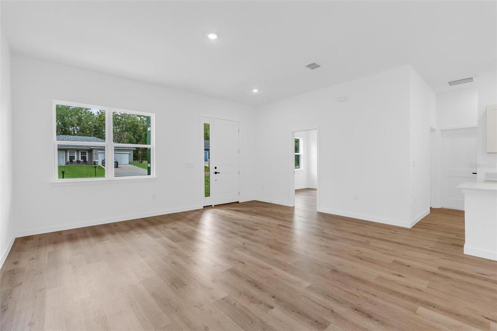 An empty room with white walls, wood-look flooring, a front door, and a large window — 10615 N DIDISCUS DRIVE, CITRUS SPRINGS, FL