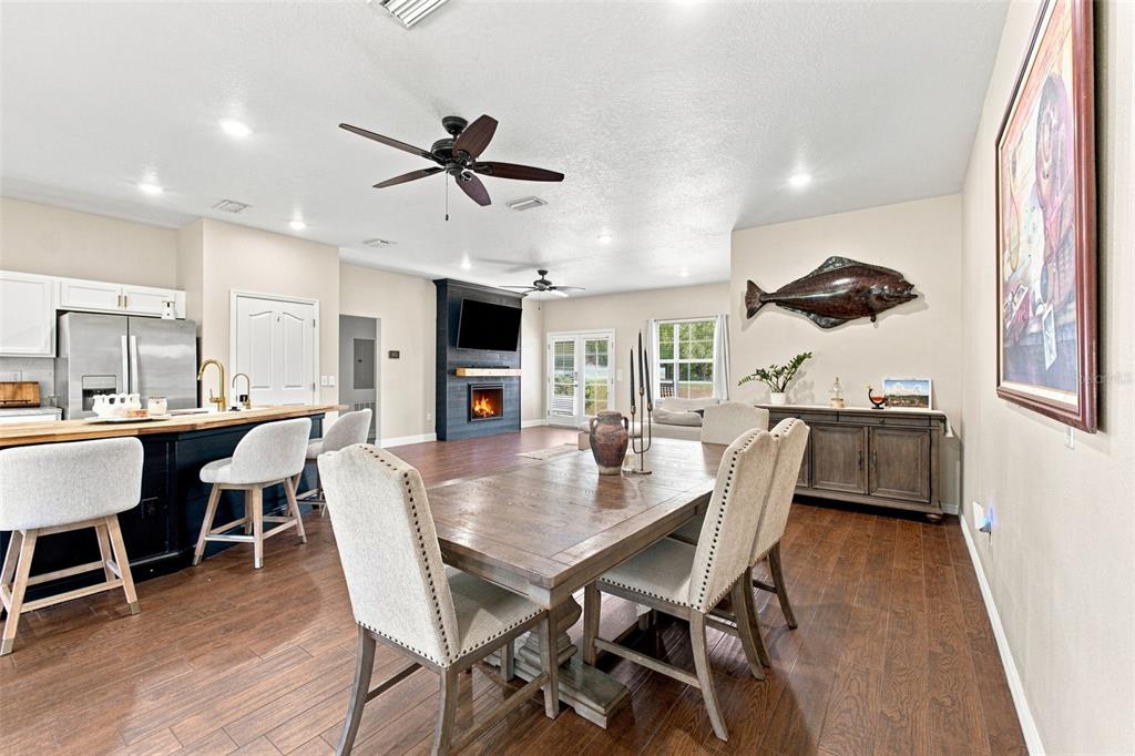 An open-concept dining and kitchen area features a wooden table, fireplace, and dark wood flooring — 10574 N SUNFLOWER POINT, CRYSTAL RIVER, FL