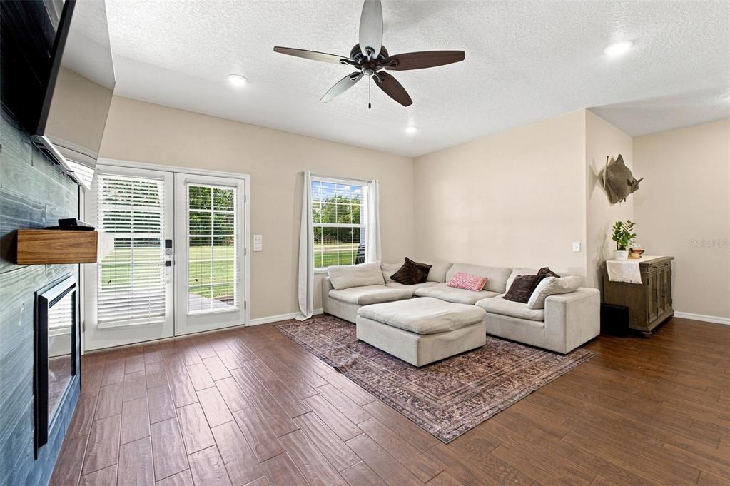 A living room features a sectional sofa, wood-look tile floors, and a ceiling fan — 10574 N SUNFLOWER POINT, CRYSTAL RIVER, FL