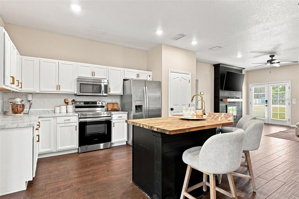 A kitchen features white cabinets, stainless steel appliances, and a black island with a wood countertop — 10574 N SUNFLOWER POINT, CRYSTAL RIVER, FL