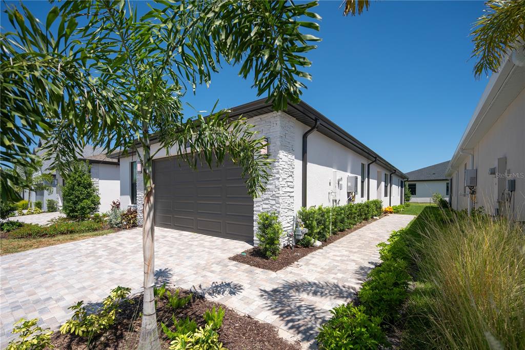 A side view of a house with a garage, stone accents, and a paved walkway — 5876 WINDBREAK COURT, APOLLO BEACH, FL