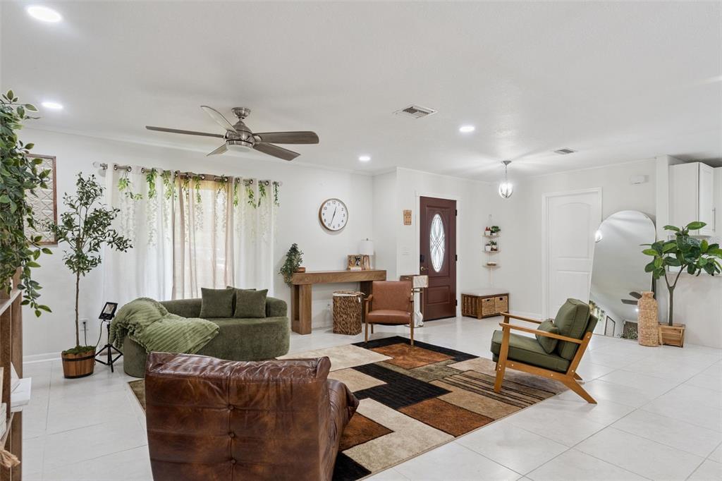 A living room features a geometric rug, green and brown seating, and a front door — 1756 TANGLEWOOD DRIVE, KISSIMMEE, FL