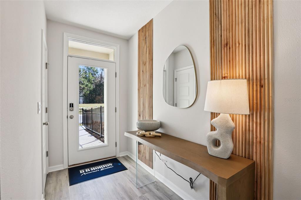 An entryway features a glass-paneled door, a wooden console table, and vertical wood slat wall accents — 148 FLAG LILLY LANE, UMATILLA, FL