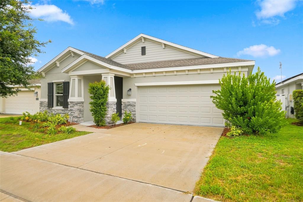 A single-story suburban house with a gray stucco exterior, stone accents, and a two-car garage — 139 PERSHING STREET, BARTOW, FL