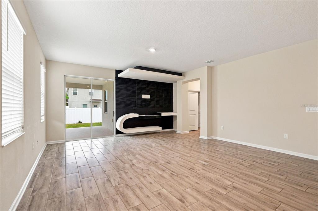 A living room features wood-look tile flooring, a textured black accent wall, and sliding glass doors — 139 PERSHING STREET, BARTOW, FL