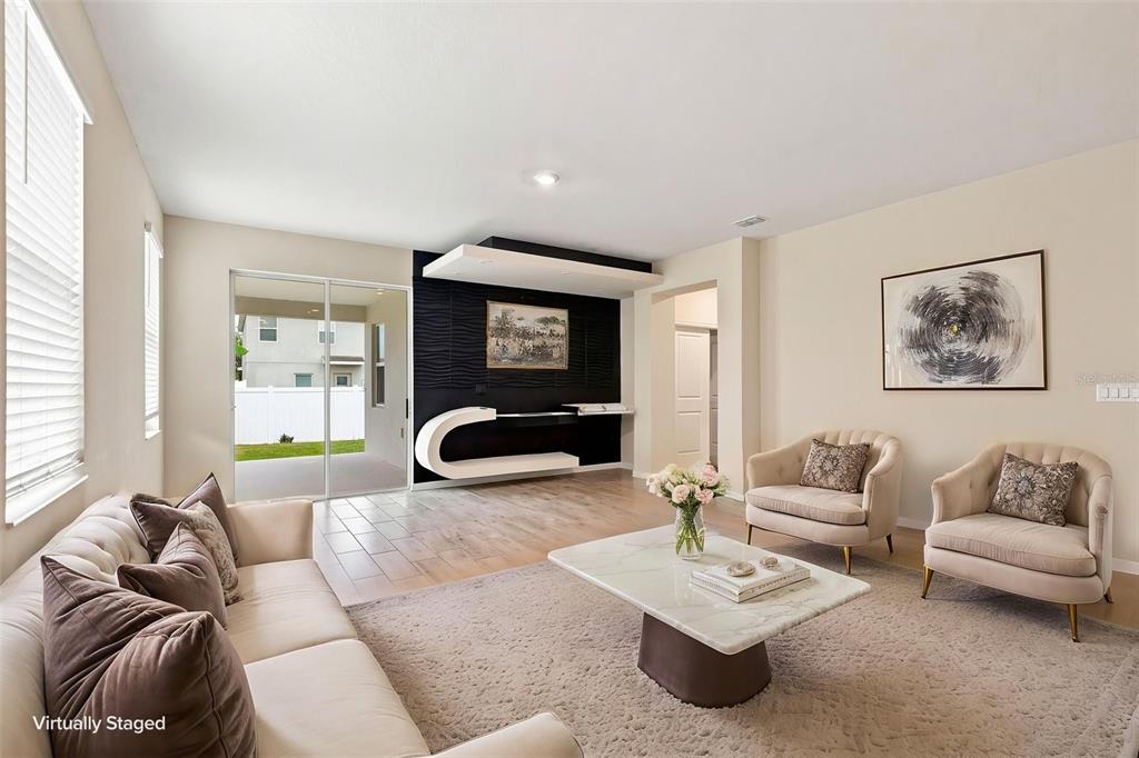 A living room features a black accent wall with a modern shelf and sliding glass doors — 139 PERSHING STREET, BARTOW, FL