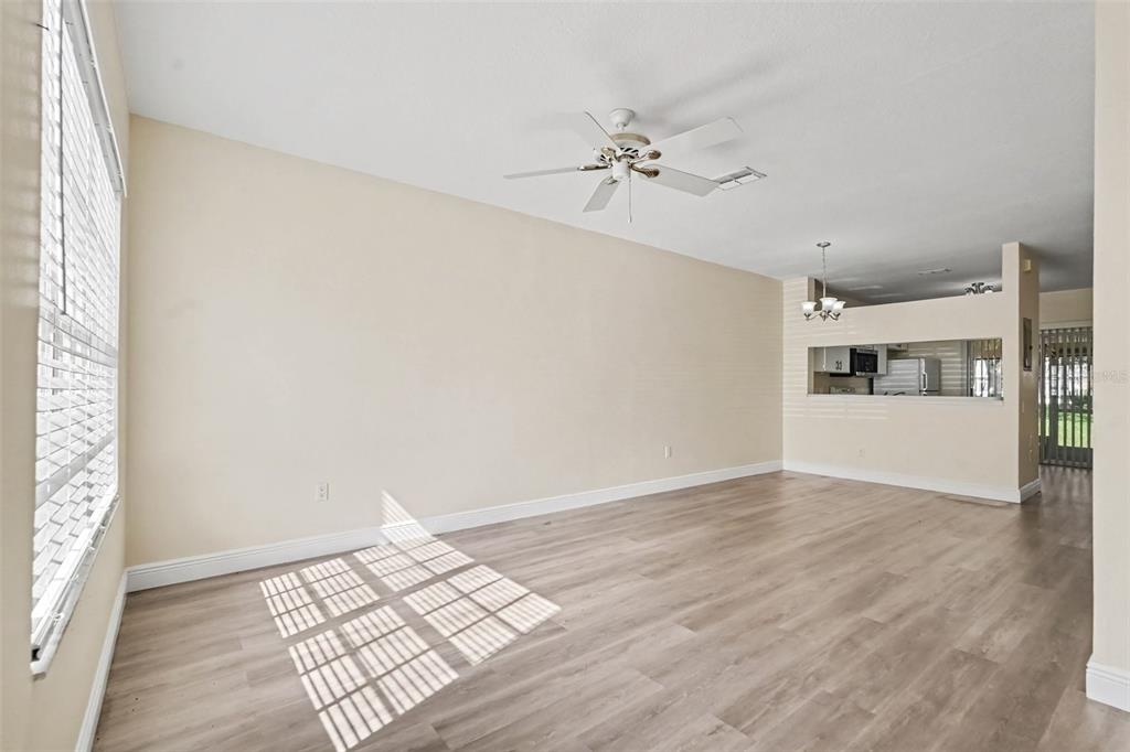 A living room features wood-look flooring, a wall-mounted television, a leather sofa, and a window — 12369 BERKELEY SQUARE DRIVE, TAMPA, FL