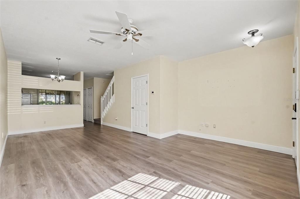 A hallway with wood-look flooring leads to a small bathroom with a toilet and step stool — 12369 BERKELEY SQUARE DRIVE, TAMPA, FL