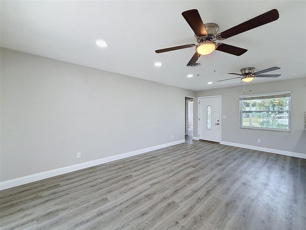 A single-story house with a light-colored exterior, a covered entryway, and landscaped front garden beds — 307 87TH AVENUE NE, ST PETERSBURG, FL
