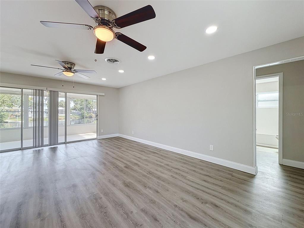 A kitchen with white cabinets and granite countertops opens to a spacious living area — 307 87TH AVENUE NE, ST PETERSBURG, FL