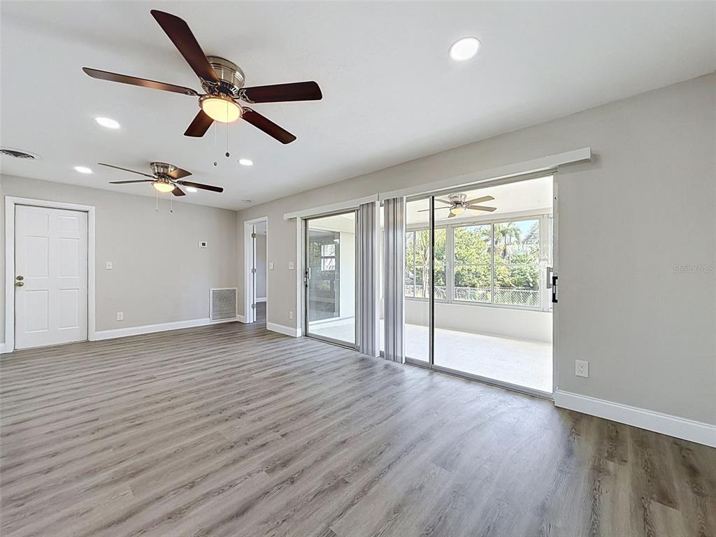 A living room with gray walls, wood-look flooring, two ceiling fans, and a front door — 307 87TH AVENUE NE, ST PETERSBURG, FL