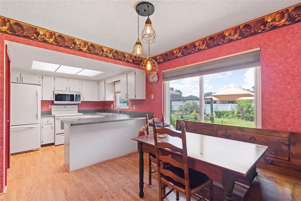 A kitchen and dining area with pink walls, white cabinets, and a wooden dining set — 1105 LENNA AVENUE, SEFFNER, FL