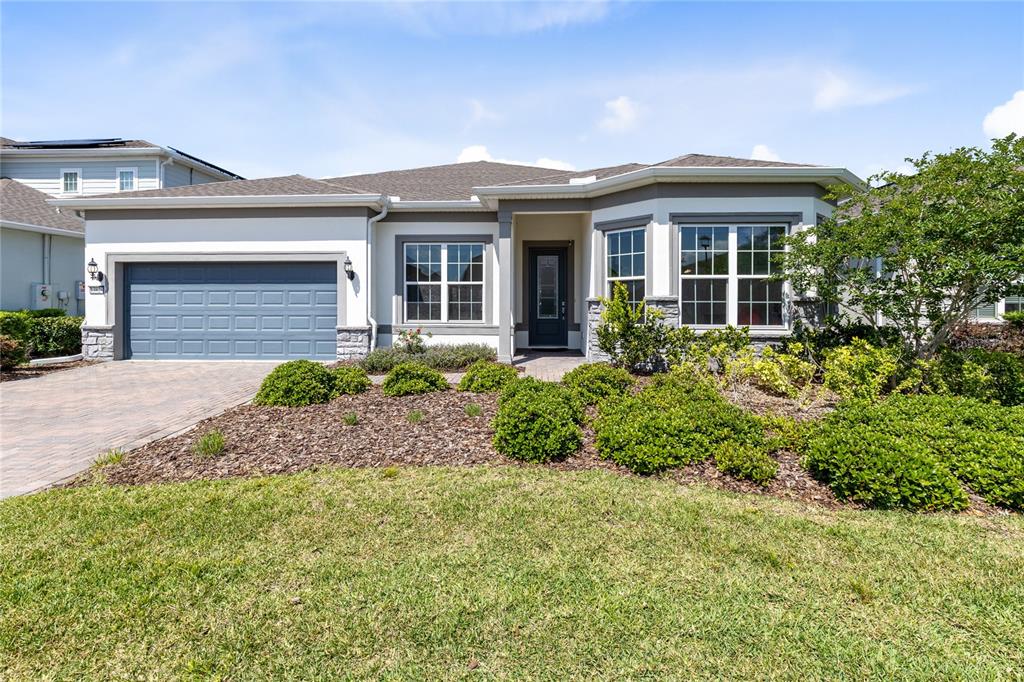 A single-story house with a gray garage, stone accents, and a landscaped front yard — 13828 TYBEE BEACH LANE, ORLANDO, FL