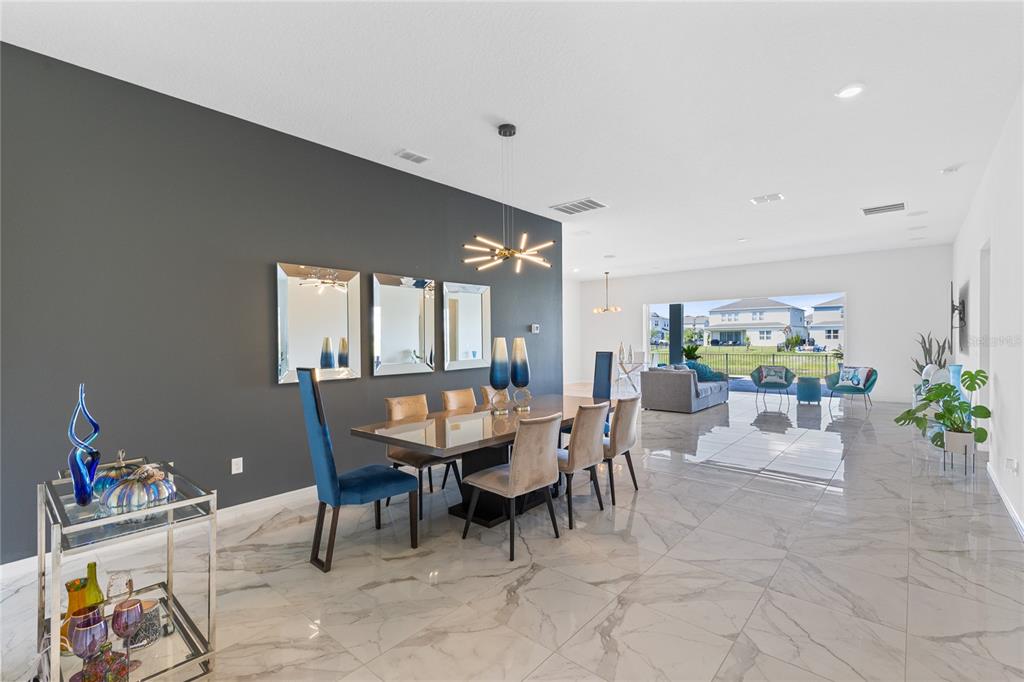 A dining area with a dark accent wall, marble floors, and a view of houses — 13828 TYBEE BEACH LANE, ORLANDO, FL