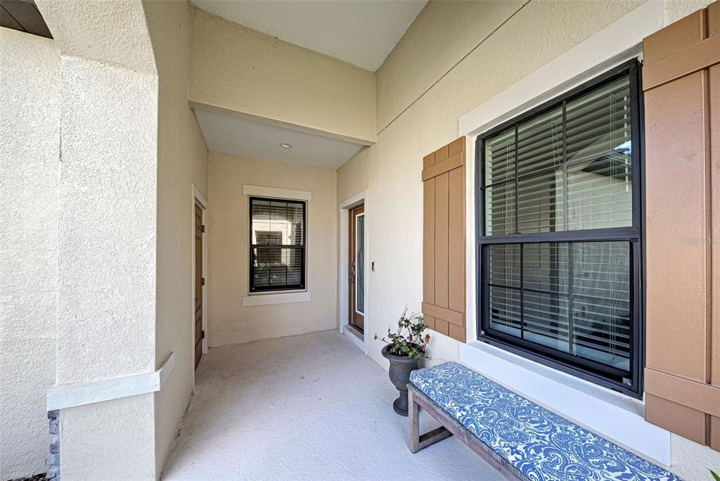 A covered entryway features a beige stucco wall, a window with brown shutters, and a bench — 233 PALIDORO CIRCLE, NOKOMIS, FL