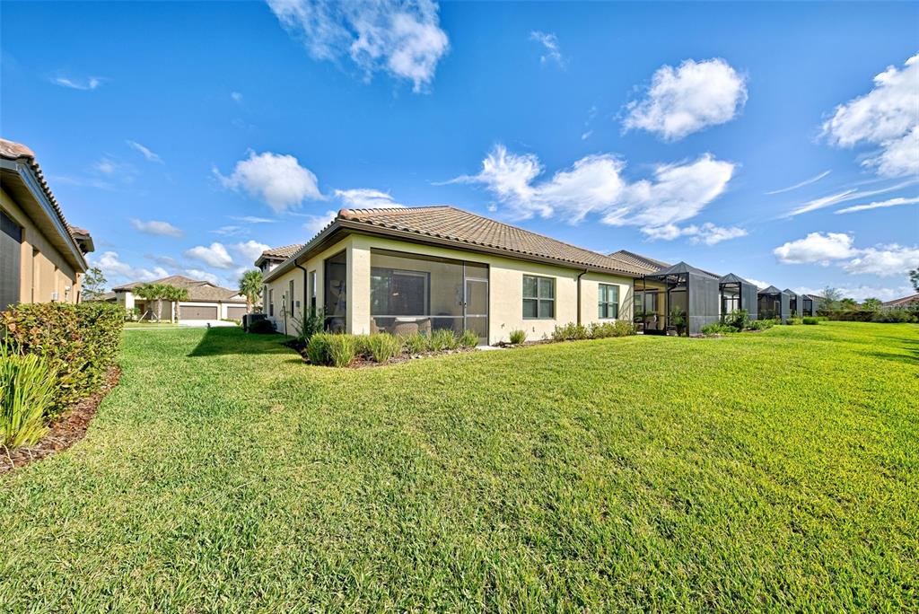The exterior of a beige house with a screened-in lanai overlooks a large grassy yard — 233 PALIDORO CIRCLE, NOKOMIS, FL