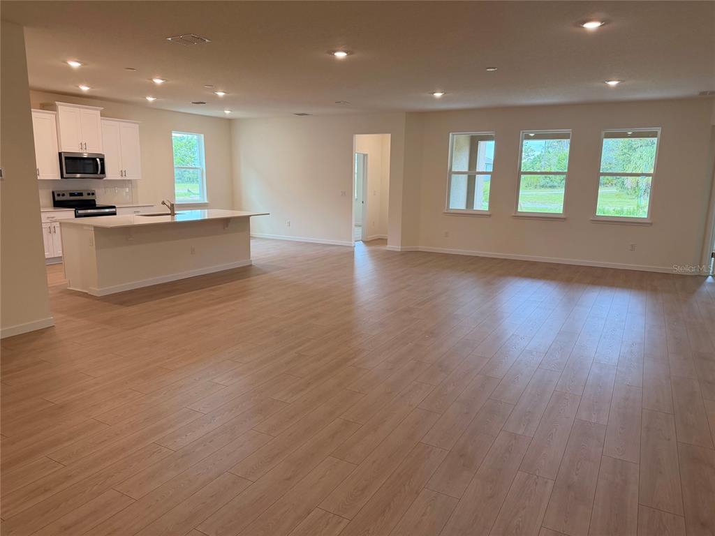 A spacious open-concept living room features a large sectional sofa, two coffee tables, and kitchen — 3042 KINGSMAN TRAIL, ORMOND BEACH, FL