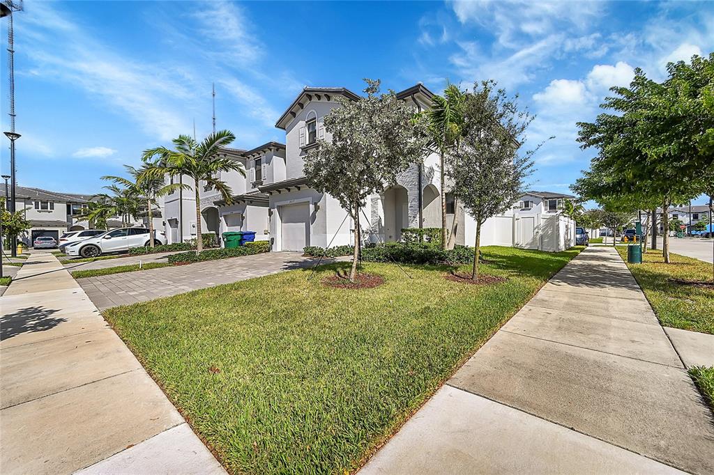 A two-story residential house with a paved driveway, a front lawn, and palm trees — 20357 NW 4TH PATH, MIAMI, FL